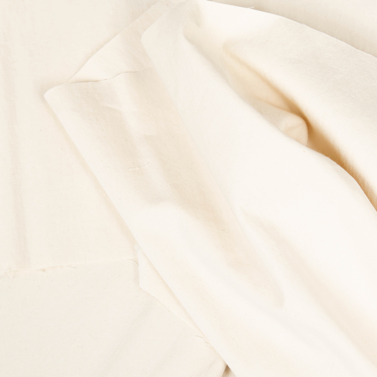 Dettaglio gabardina di puro cotone color crema, tessuto lavato con caratteristica trama diagonale, perfetto per abbigliamento sartoriale