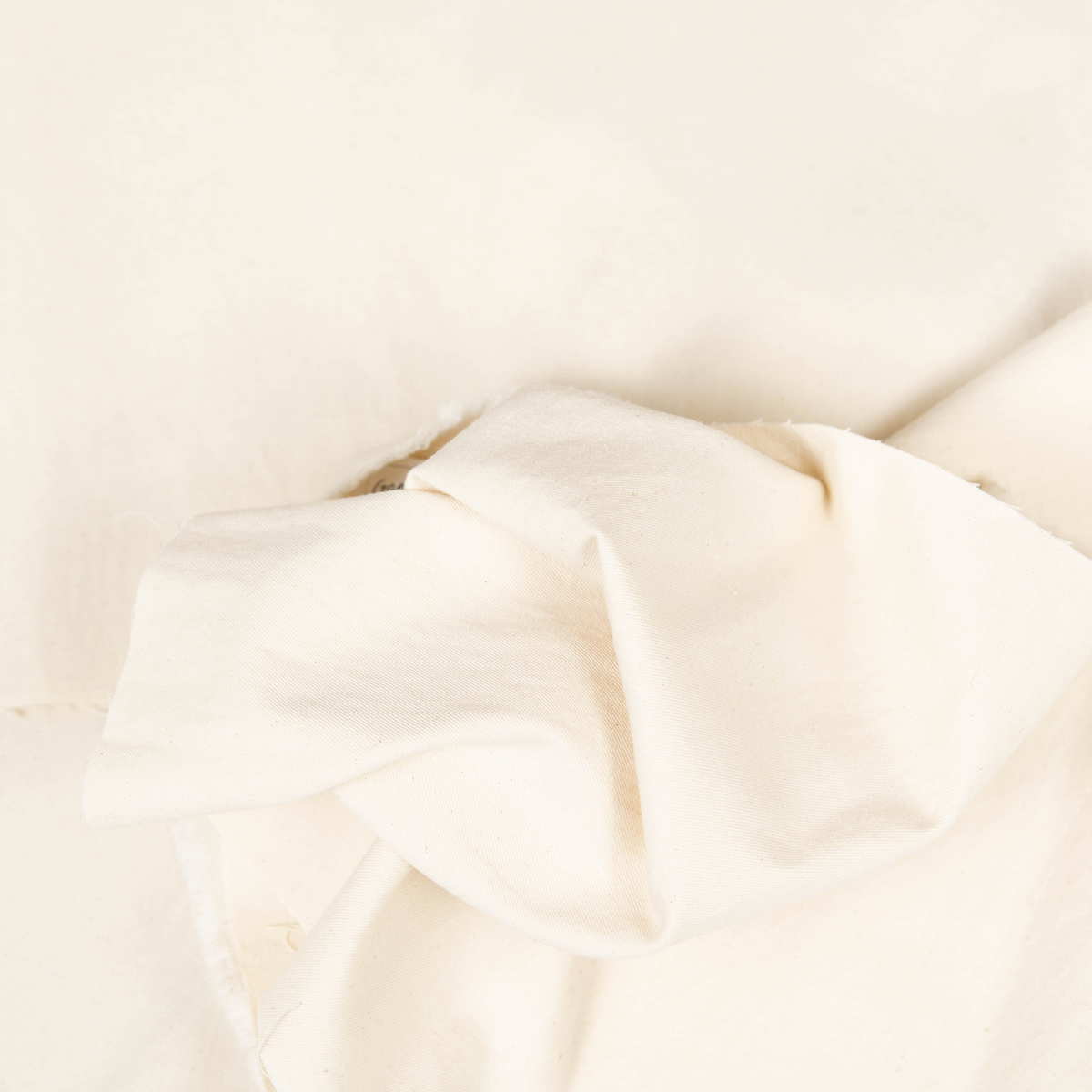 Tessuto gabardina lavata color crema in 100% cotone, dalla mano morbida e struttura compatta, ideale per pantaloni sartoriali, giacche e trench.