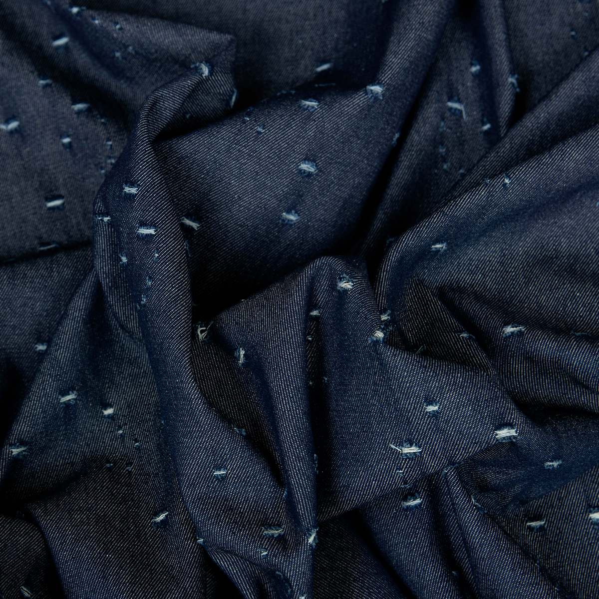 Tessuto denim blu scuro 100% cotone con microfori laser decorativi.