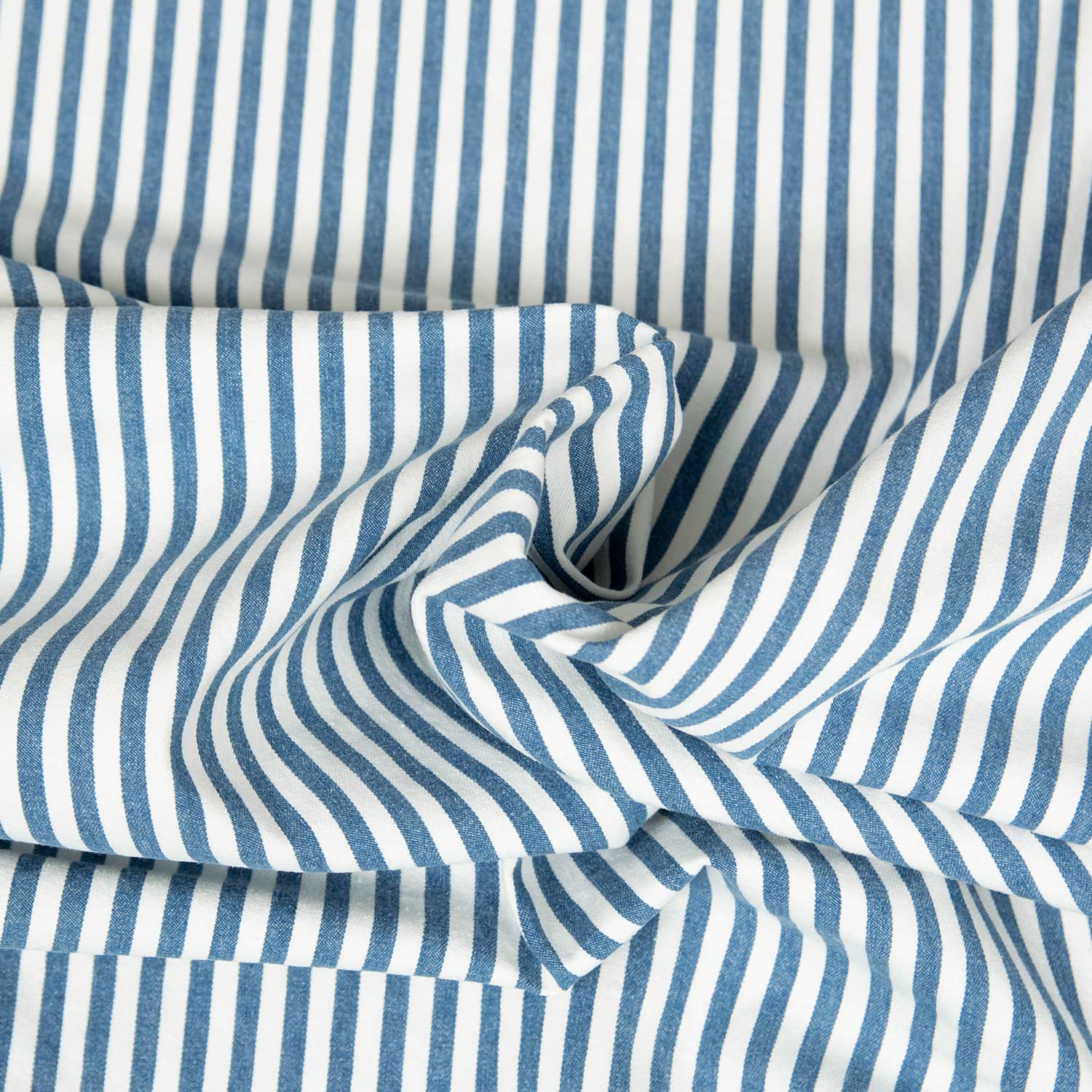Tessuto jeans stretch a righe verticali blu e bianche lavato, texture morbida, drappeggiato per mostrare la fluidità e l'elasticità del tessuto workwear contemporaneo
