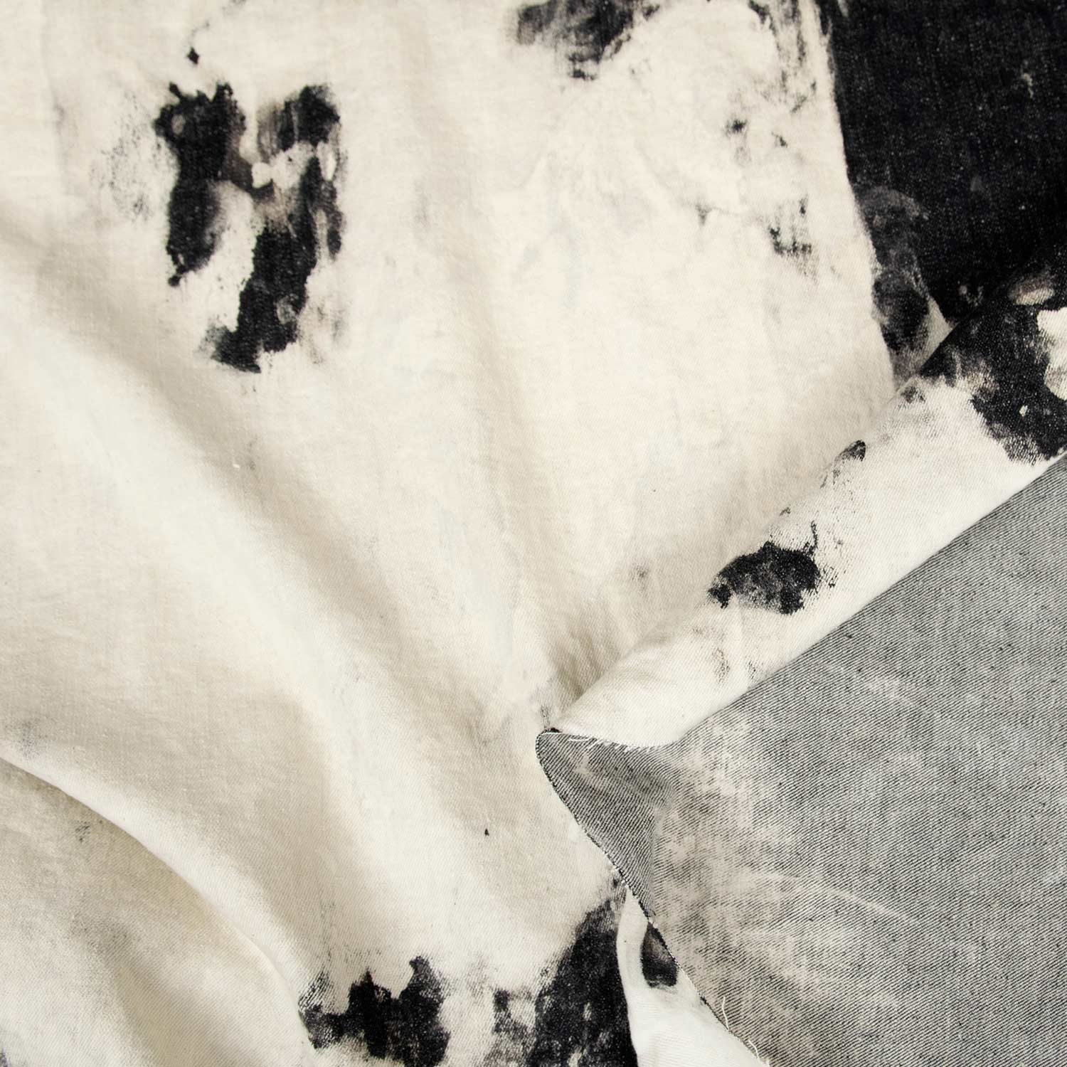 Close-up di tessuto denim con effetto tie-dye artigianale nero su base chiara