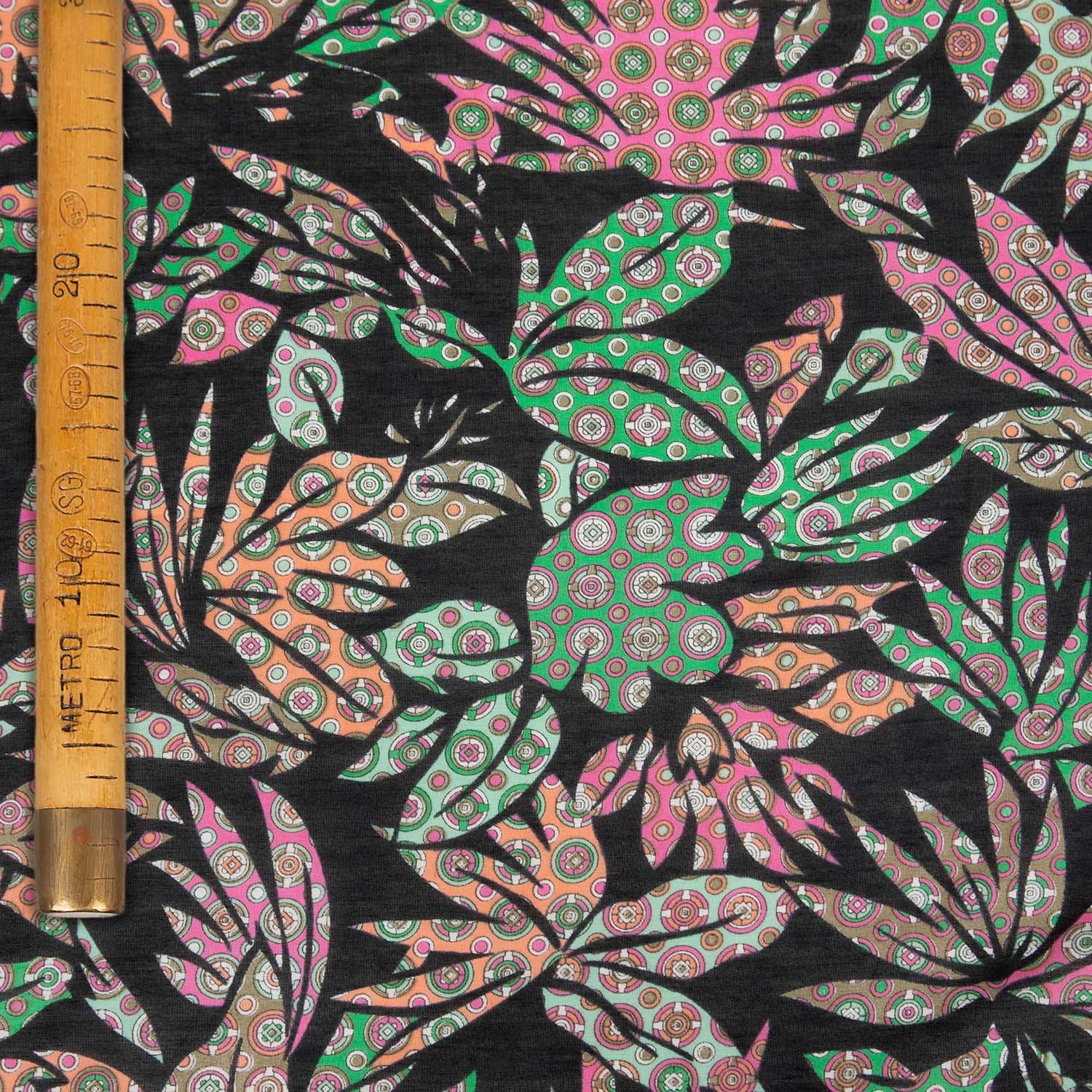 Tessuto mussola seta cotone molto leggero con fantasia foglie rosa, verdi e arancio su base nera, ideale per abiti estivi e parei, venduto al metro.