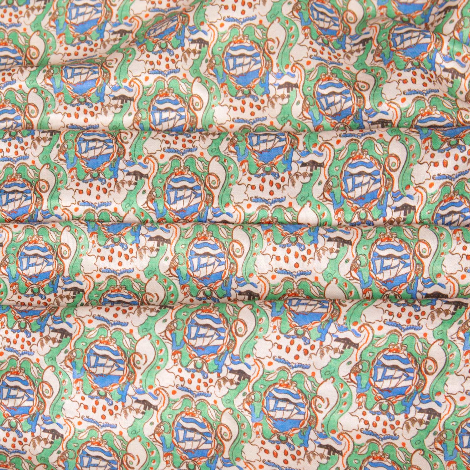 Tessuto al metro in raso morbido, lucido e leggero, con pattern sognante e atmosfere fiabesche in verde, azzurro e rosso su base beige.