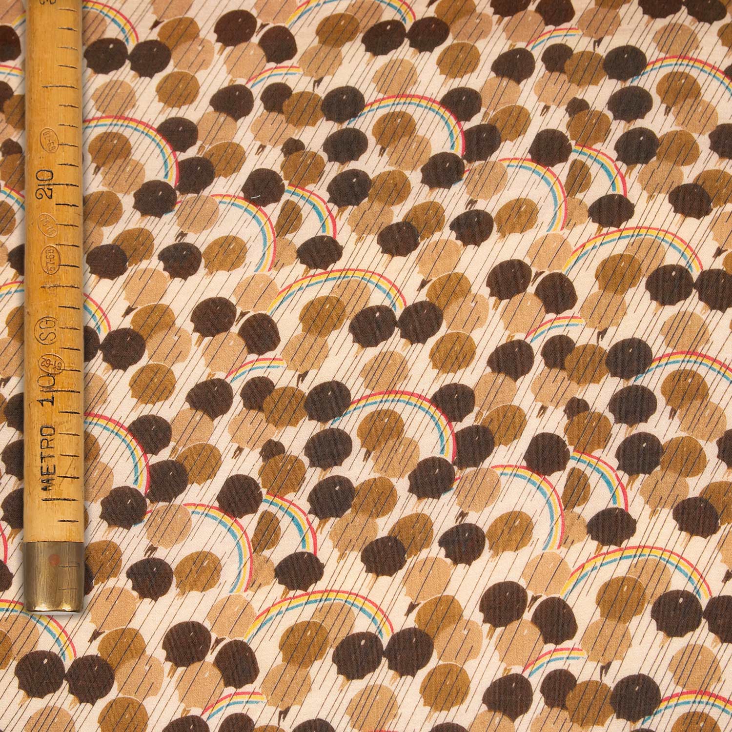 Dettaglio con il metro per riferimento stampa di tessuto in raso cotone seta lucido e fluido con fantasia all-over su fondo chiaro.