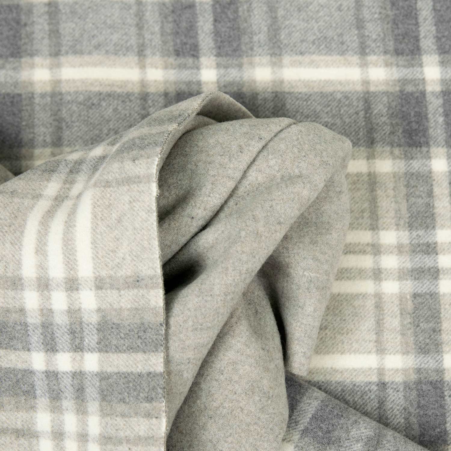 Dettaglio di tessuto misto cashmere grigio chiaro a quadri, con disegno tono su tono e righe bianche.