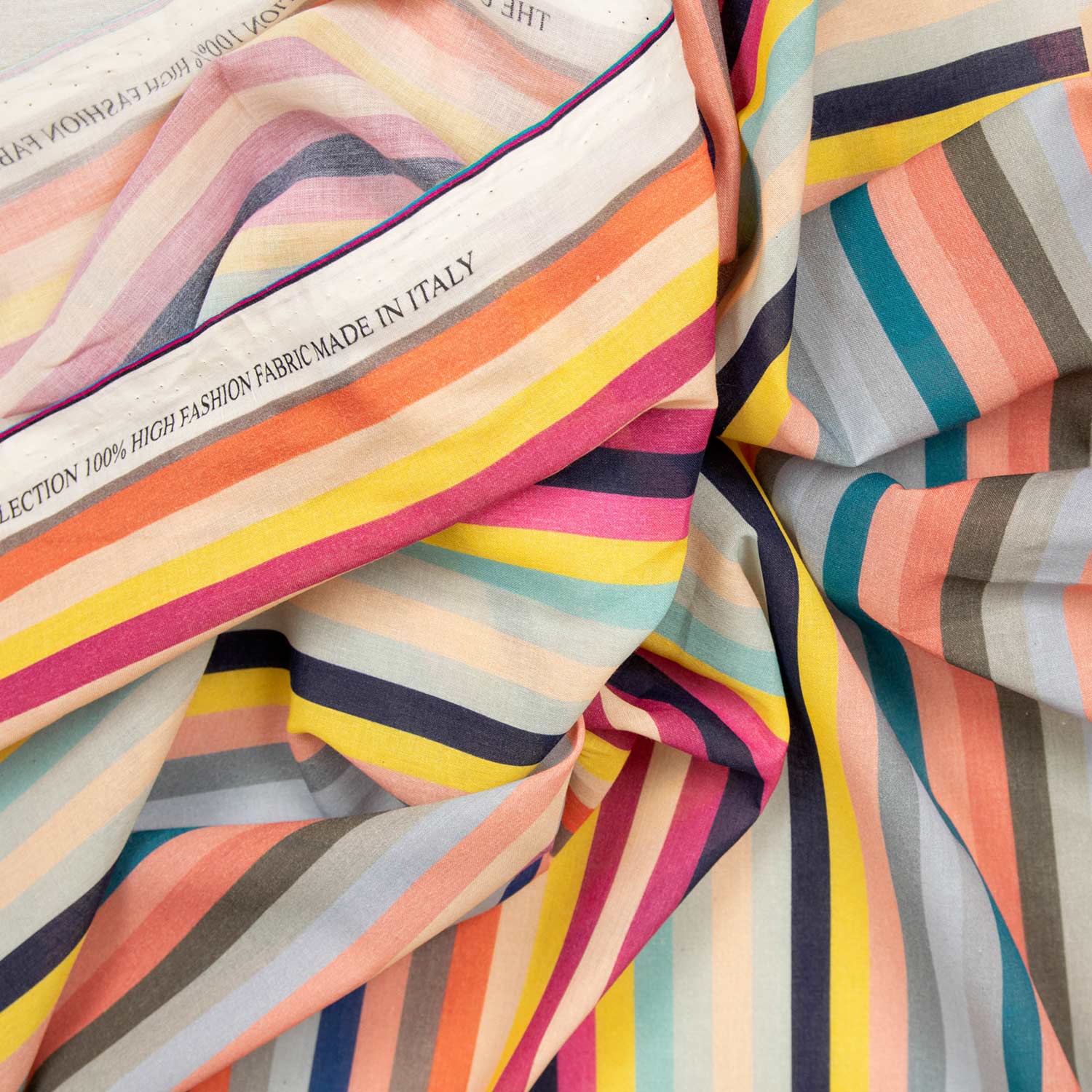 Dettaglio cimosa mussola cotone 100% Made in Italy con stampa a righe multicolor, tessuto deadstock alta moda produzione italiana