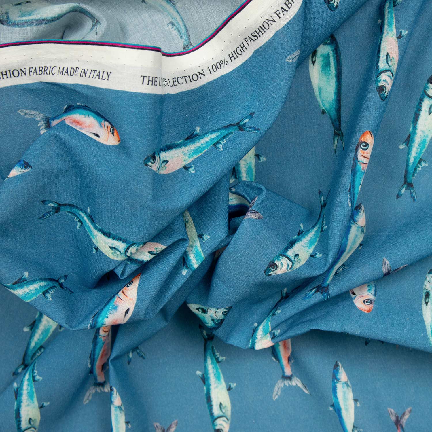 Mussola cotone Made in Italy drappeggiata con cimosa visibile, stampa a sardine acquerellate su fondo blu oceano, high fashion fabric produzione italiana