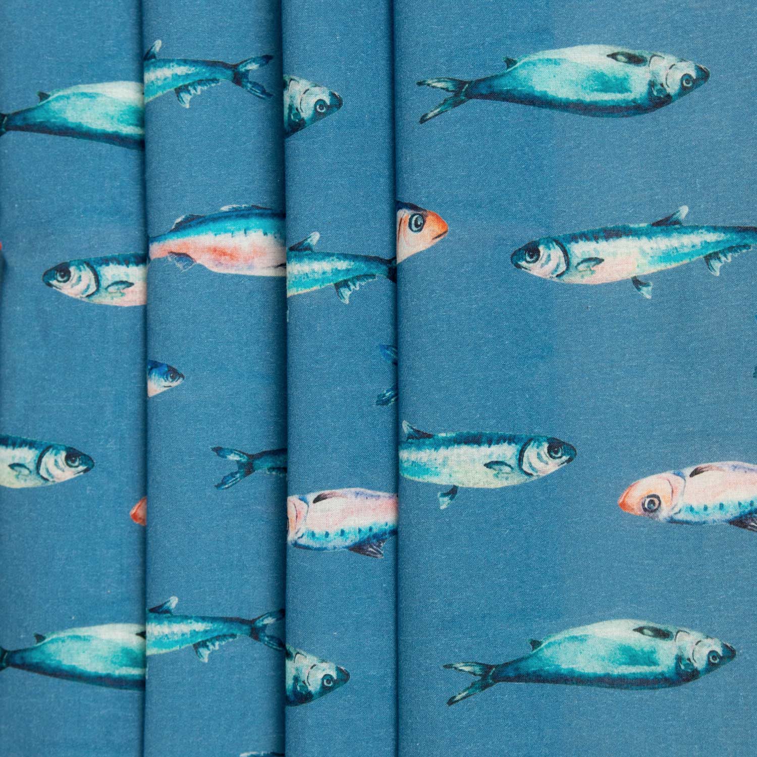 Mussola cotone stampata deadstock con sardine mediterranee su fondo blu petrolio, tessuto piegato in più strati che mostra la consistenza e la qualità del cotone leggero