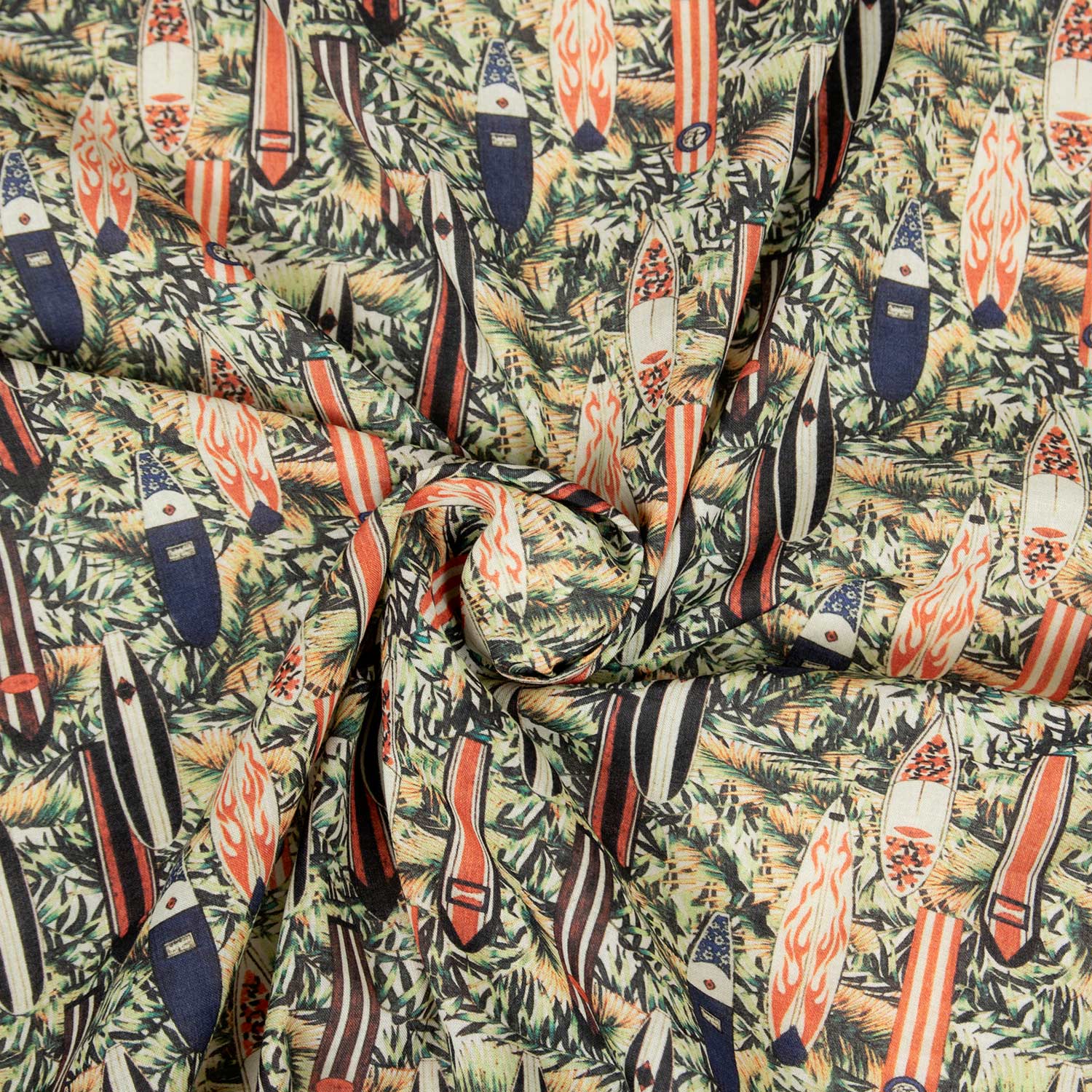 Mussola 100% cotone deadstock con stampa surf vintage, tavole da surf retrò e foglie tropicali su fondo naturale, tessuto arrotolato che mostra la morbidezza e la caduta fluida del cotone leggero estivo