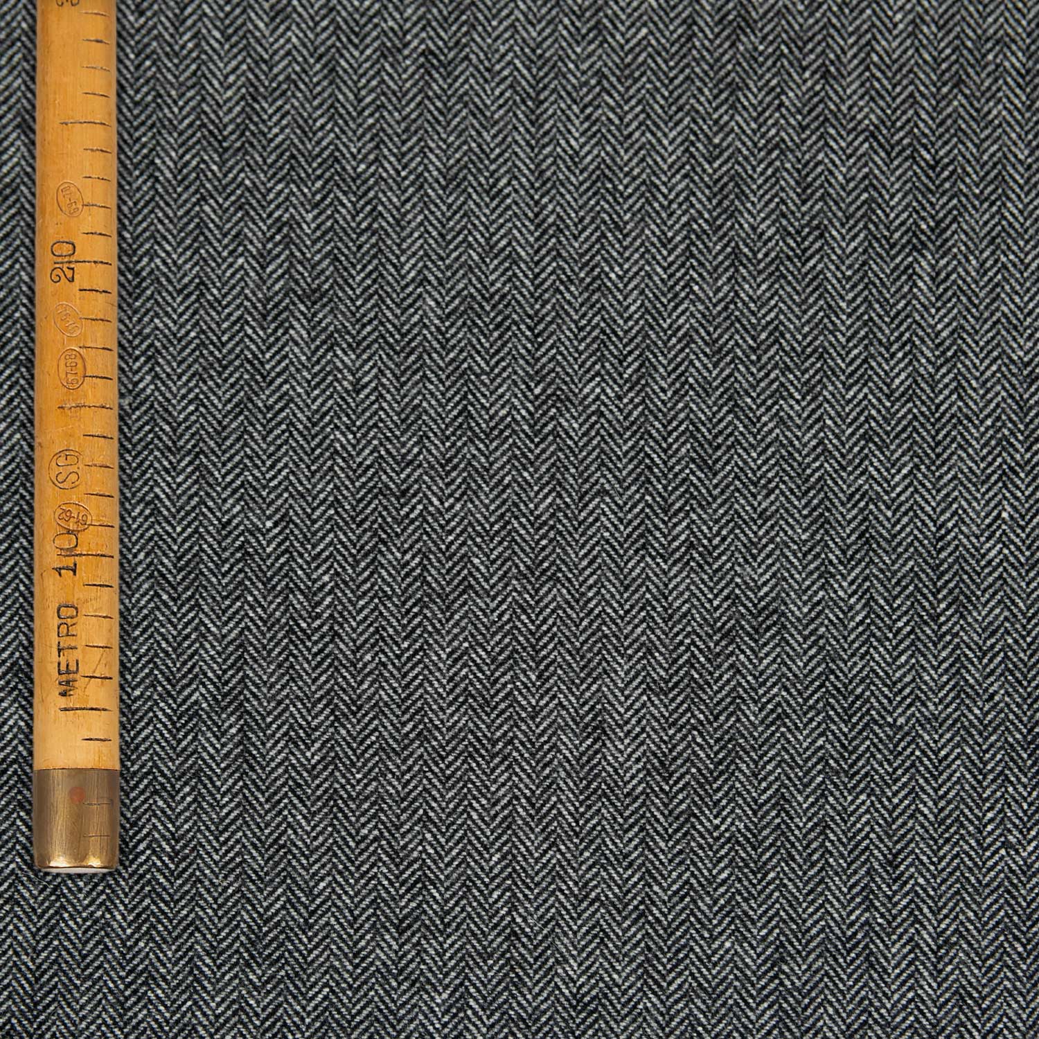Dettaglio del tessuto Herringbone grigio in lana riciclata, motivo spina di pesce, finitura elegante e mano soffice per blazer e capispalla.