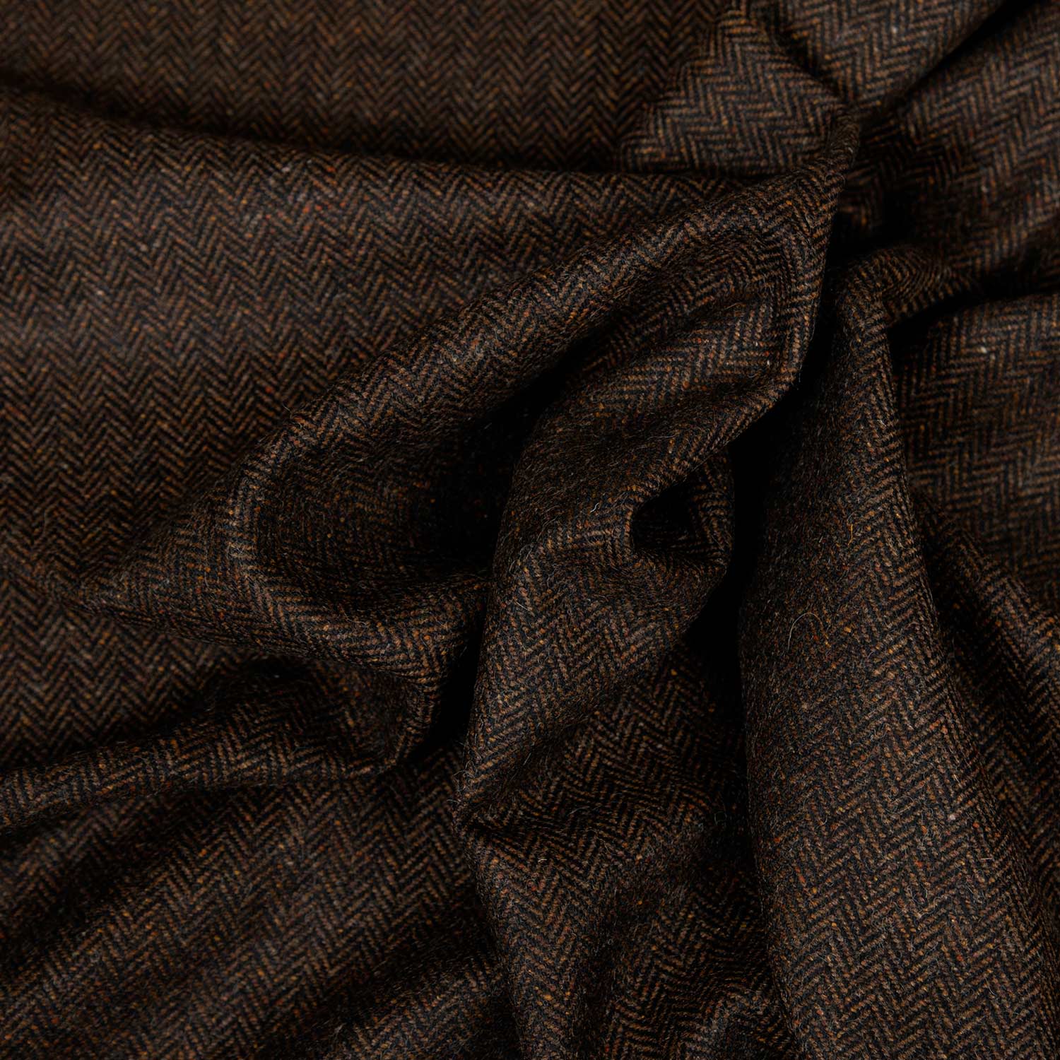 Primo piano del tessuto Herringbone marrone in lana riciclata, trama chevron raffinata e mano morbida per abbigliamento di qualità.