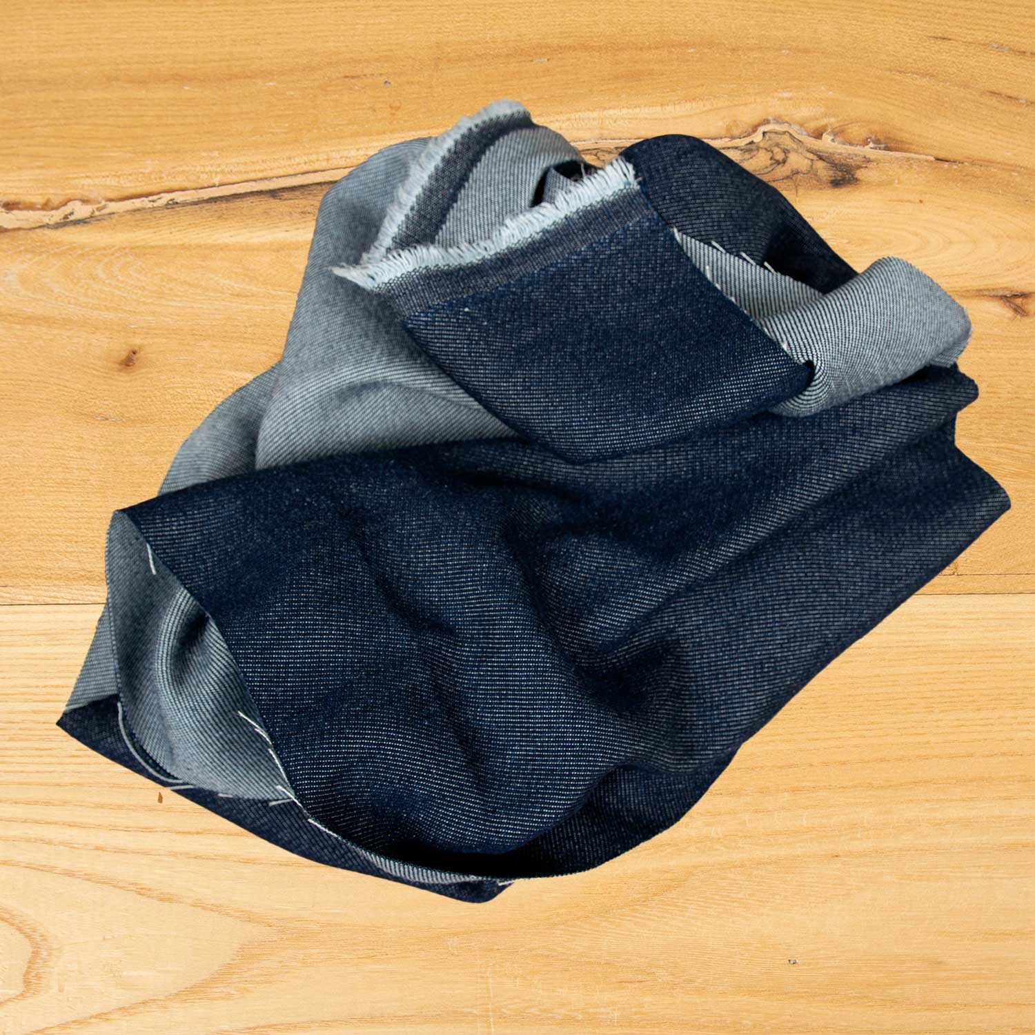 Dettaglio del denim in Tencel blu scuro con effetto lavato naturale, tessuto resistente e confortevole per abbigliamento contemporaneo.