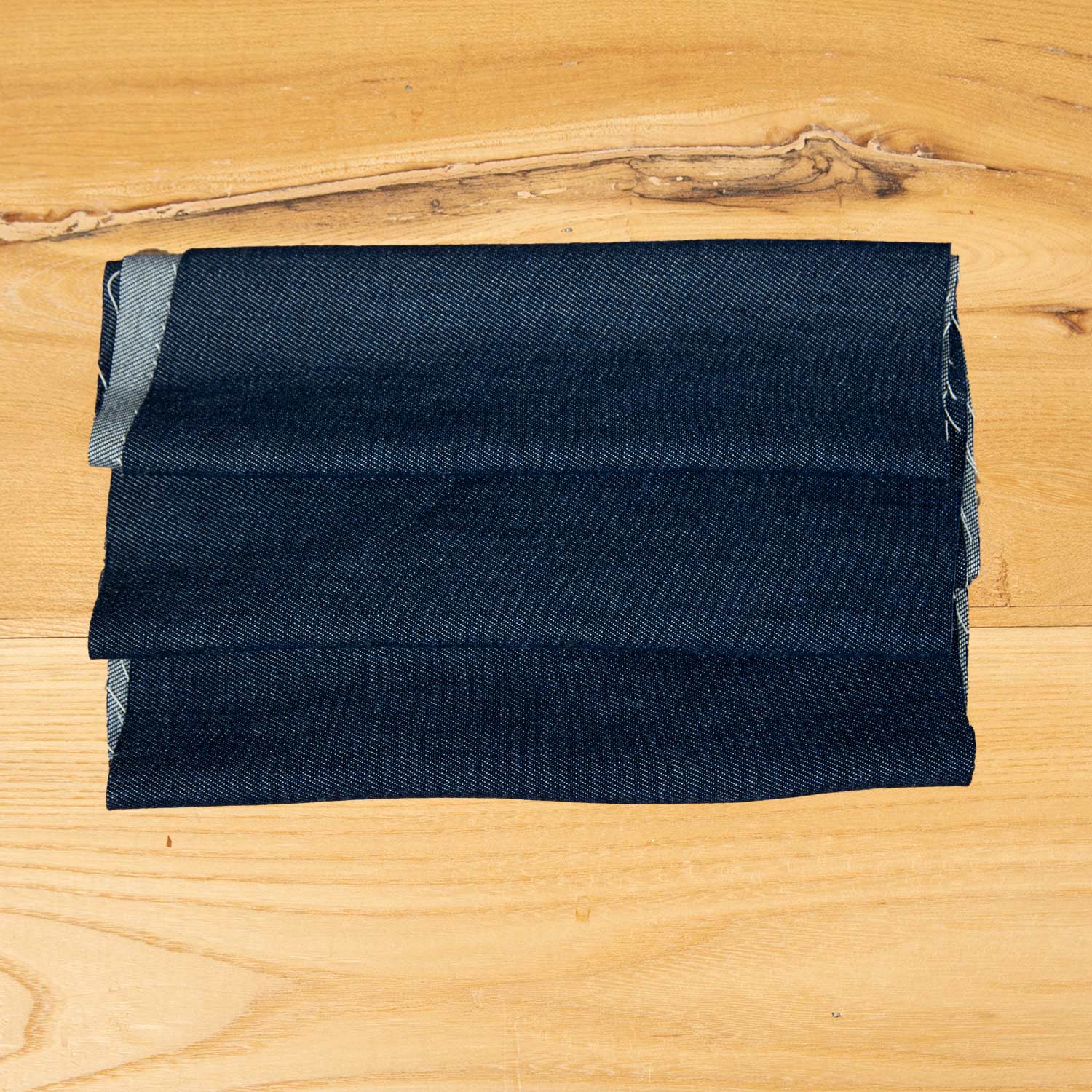 Primo piano tessuto denim blu scuro lavato in fibra Tencel 100%, mano morbida e struttura compatta per overshirt, pantaloni e capispalla.