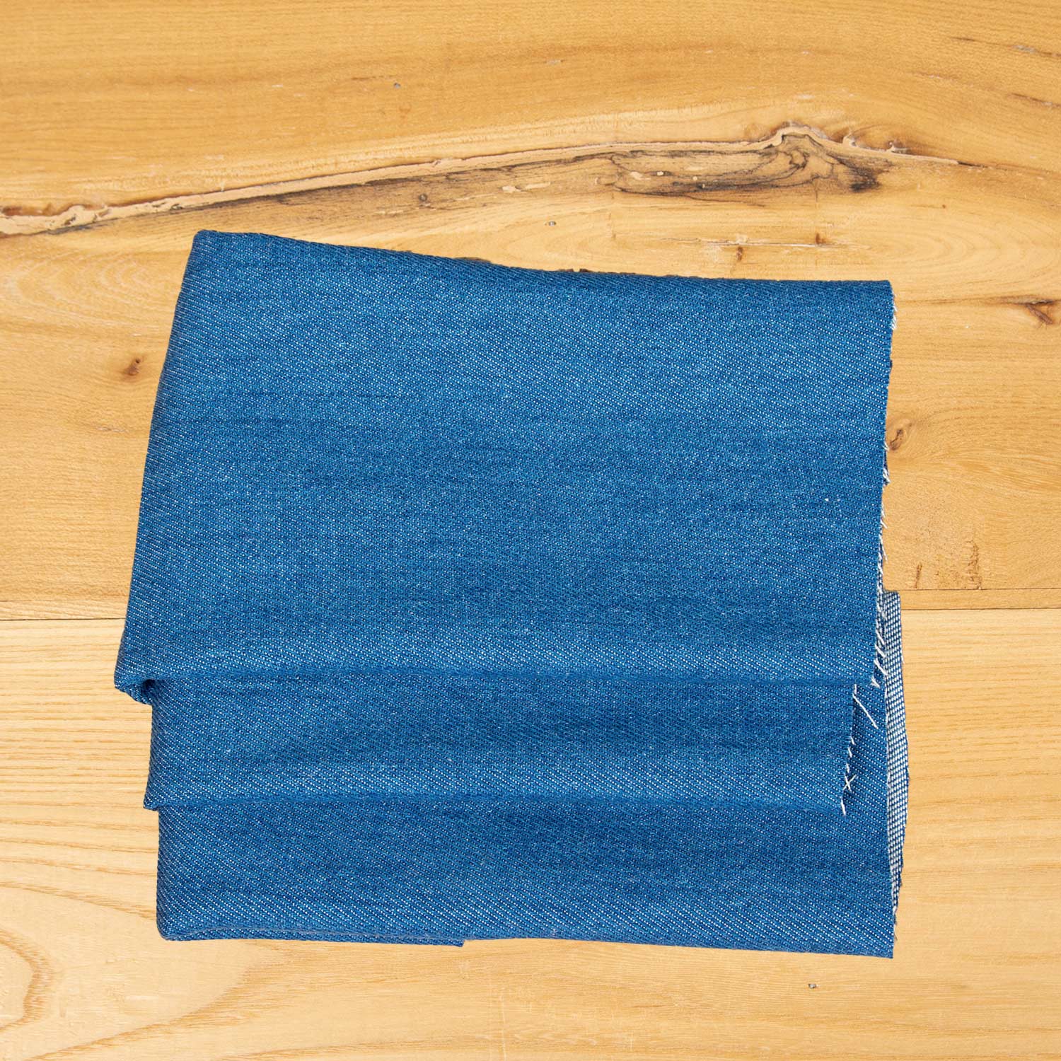 Dettaglio del denim in Tencel blu chiaro con effetto lavato naturale, tessuto deadstock dalla mano morbida per abbigliamento contemporaneo.