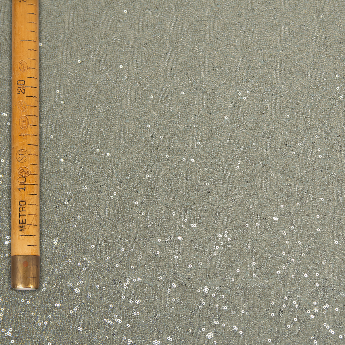 Dettaglio di tessuto a paillettes argento con effetto cangiante e movimento sinuoso, ideale per abiti da sera e creazioni di alta moda